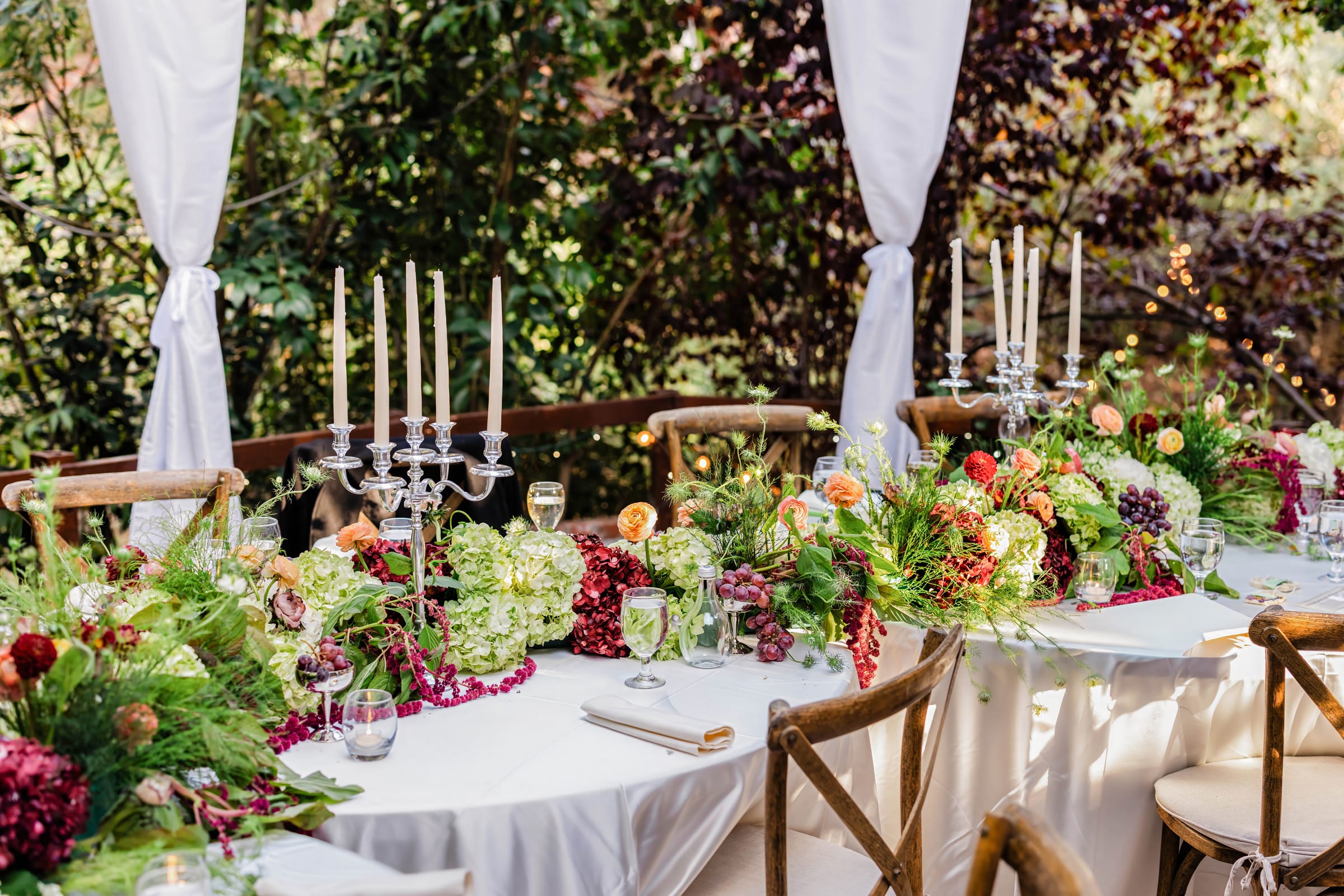 Candlelit banquet table set for a celebration in the garden