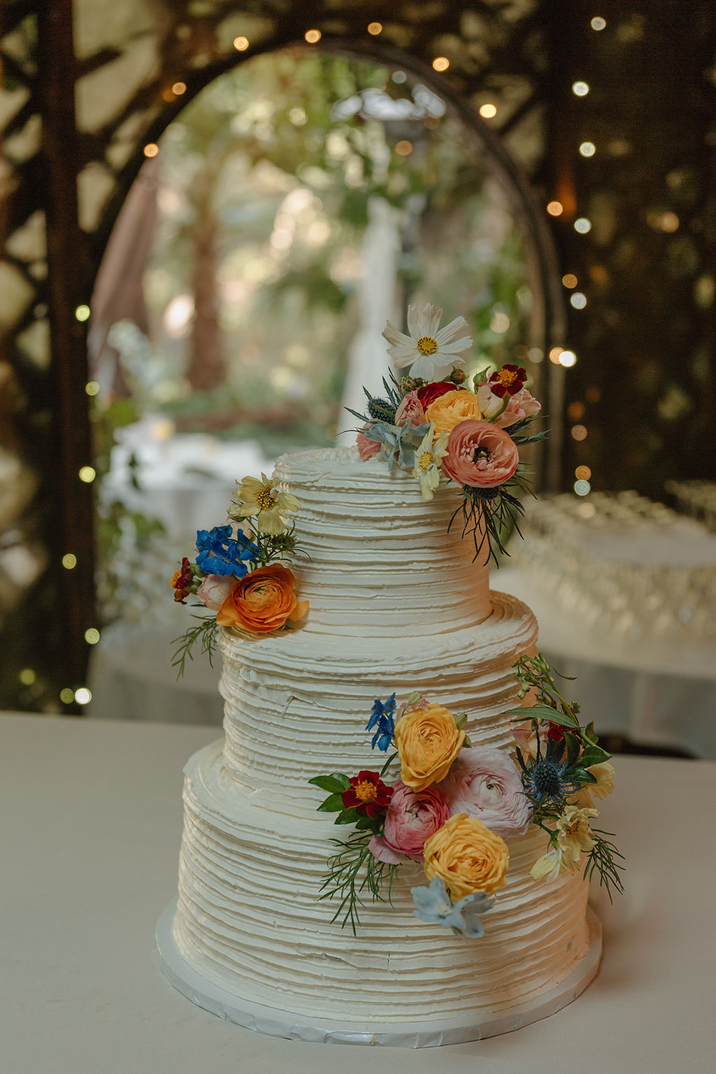 Wedding cake with garden flowers beneath the arbor